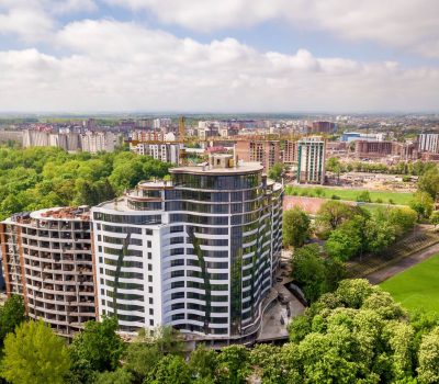 apartment-or-office-tall-building-unfinished-under-construction-among-green-tree-tops.jpg
